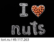 Peanuts on a black background and chalk inscription "I love nuts". Heart drawn in chalk and peanuts. Стоковое фото, агентство Ingram Publishing / Фотобанк Лори