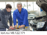 student with instructor repairing a car during apprenticeship. Стоковое фото, агентство Ingram Publishing / Фотобанк Лори