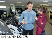 Woman in conversation with salesman in scooter showroom. Стоковое фото, агентство Ingram Publishing / Фотобанк Лори