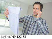Builder phoning architect to check plans. Стоковое фото, агентство Ingram Publishing / Фотобанк Лори