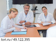 Medics sat around table in discussion. Стоковое фото, агентство Ingram Publishing / Фотобанк Лори