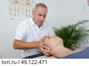 physiotherapist massages holding male clients head. Стоковое фото, агентство Ingram Publishing / Фотобанк Лори