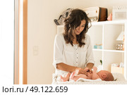 Mother changing a diaper on newborn baby. Стоковое фото, агентство Ingram Publishing / Фотобанк Лори