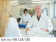 Dry cleaner returning garment to customer. Стоковое фото, агентство Ingram Publishing / Фотобанк Лори
