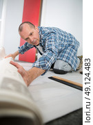 man unrolling carpert on the floor of a house. Стоковое фото, агентство Ingram Publishing / Фотобанк Лори