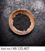 Black cumin seeds in rustic bowl on dark vintage background, top view. Nigella sativa seeds. Стоковое фото, агентство Ingram Publishing / Фотобанк Лори