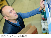 sales assistant shelving spray cans at hardware store. Стоковое фото, агентство Ingram Publishing / Фотобанк Лори