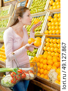 Young woman holding and smelling oranges from a stall. Стоковое фото, агентство Ingram Publishing / Фотобанк Лори