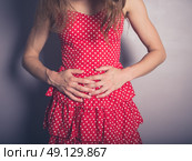 A young woman is touching her stomach because she has a belly ache. Стоковое фото, агентство Ingram Publishing / Фотобанк Лори