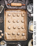 Cookies to form balls on baking tray preparation on kitchen table background with ingredients and Dough roll , top view. Стоковое фото, агентство Ingram Publishing / Фотобанк Лори