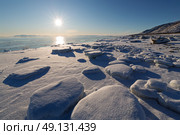 Зимний морской пейзаж. Вид на льдины на берегу моря. На переднем плане покрытый снегом лёд. Вдали незамёрзшее море. Яркий солнечный свет. Холодная погода. Побережье Охотского моря, Магаданская область, Россия. Стоковое фото, фотограф Андрей Степанов / Фотобанк Лори