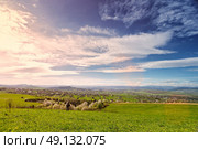Traveler on green spring meadow. Village on sunny green spring foothills. Orchard blooming on hills. Sunny green blooming spring landscape. Стоковое фото, агентство Ingram Publishing / Фотобанк Лори