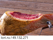 Iberian ham pata negra from Spain cut by hand on wood. Стоковое фото, агентство Ingram Publishing / Фотобанк Лори