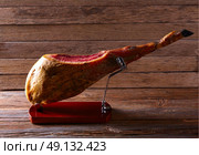 Iberian ham pata negra from Spain on wood background. Стоковое фото, агентство Ingram Publishing / Фотобанк Лори