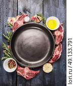 Empty plate with raw lamb loin chops meat , oil, herb and spices on  blue wooden background, top view. Стоковое фото, агентство Ingram Publishing / Фотобанк Лори
