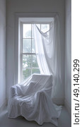 A white bed is positioned under a window next to a white curtain. Стоковое AI-изображение, AI-художник Данила Большаков / Фотобанк Лори