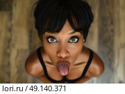 A woman is making a funny face by sticking out her tongue with a playful expression. Стоковое AI-изображение, AI-художник Данила Большаков / Фотобанк Лори