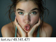 A woman playfully contorts her face while holding her hands in a humorous gesture. Стоковое AI-изображение, AI-художник Данила Большаков / Фотобанк Лори