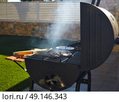 Barbecue with smoke side view in a masonry turf backyard. Стоковое фото, агентство Ingram Publishing / Фотобанк Лори