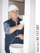 senior man painting a wall at construction site. Стоковое фото, агентство Ingram Publishing / Фотобанк Лори