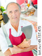Butcher holding knife and cleaver, arms crossed. Стоковое фото, агентство Ingram Publishing / Фотобанк Лори