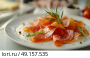 Enjoy a platter of Italian Prosciutto Ham garnished with grapes and fresh herbs for a flavorful culinary experience. Стоковое AI-изображение, AI-художник Anastasy Yarmolovich / Фотобанк Лори