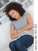 woman suffering stomach-ache sitting on sofa in the living room. Стоковое фото, агентство Ingram Publishing / Фотобанк Лори