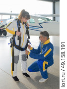 Man fastening straps on parachutist’s harness. Стоковое фото, агентство Ingram Publishing / Фотобанк Лори