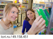 cheerful young girl and friend choosing pencils at a stationary. Стоковое фото, агентство Ingram Publishing / Фотобанк Лори