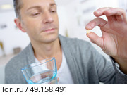 man taking a pill with glass of water. Стоковое фото, агентство Ingram Publishing / Фотобанк Лори