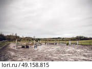 Horse riding track with jump hurdles in an arena with sand in dark cloudy weather. Стоковое фото, агентство Ingram Publishing / Фотобанк Лори
