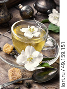soothing tea with Jasmine flowers. glass of herbal tea with the aroma of Jasmine flower on wooden background. Стоковое фото, агентство Ingram Publishing / Фотобанк Лори