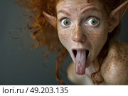 A red-haired, freckled woman with pointed ears sticks her tongue out playfully while making a silly face against a dark indoor background. Стоковое AI-изображение, AI-художник Данила Большаков / Фотобанк Лори