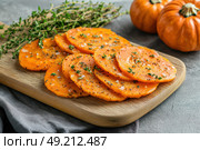 Cutting Fresh Pumpkins on Board. Baked pumpkin. Sliced raw Cucurbita maxima and spices for preparing soup, warm salad, fall dish. Thanksgiving food. Roasted vegetable in olive oil salt pepper, herbs. Стоковое AI-изображение, AI-художник Марина Демидюк / Фотобанк Лори