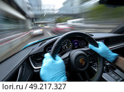 A man is driving a car with a blue steering wheel and wearing blue gloves. Стоковое AI-изображение, AI-художник Ярославский Максим / Фотобанк Лори
