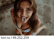 A woman sticks out her tongue in a humorous expression, with a playful and silly demeanor. Стоковое AI-изображение, AI-художник Данила Большаков / Фотобанк Лори