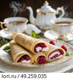 Вкусные блинчики с малиной, поданные с чаем в элегантных чашках, демонстрирующие уютный обеденный опыт. Стоковое AI-изображение, AI-художник Наталья Харинова / Фотобанк Лори
