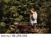Woman Enjoys Grilling Outdoors in a Cozy Backyard Surrounded by Greenery. Стоковое фото, фотограф Aleksandr Golubev / Фотобанк Лори