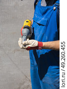 A worker in a blue jumpsuit is preparing to fix a slate sheet using an electric screwdriver with a riveter attachment and an exhaust construction rivet. Стоковое фото, фотограф Неведицына Елена / Фотобанк Лори