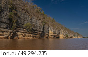 A calm red-brown African river with steep limestone banks. Green vegetation, trees on eroded slopes. Clear blue sky. Diagonally. Copy space. Madagascar. Manambolo river. (2023 год). Стоковое фото, фотограф Вера Ивановна Кубарева / Фотобанк Лори