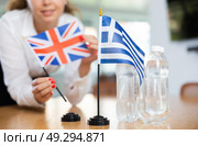 Unrecognizable girl sets midget flags of Greece and Great Britain before international negotiations. Стоковое фото, фотограф Яков Филимонов / Фотобанк Лори