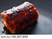 Grilled smoked eel on black plate macro closeup detail. Стоковое фото, агентство Ingram Publishing / Фотобанк Лори