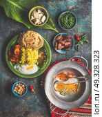 Indian food meals in bowls served with banana leaf: Curry, butter chicken, rice, lentils, paneer, samosa, naan, chutney, spices.  Traditional south indian cuisine. Стоковое фото, агентство Ingram Publishing / Фотобанк Лори