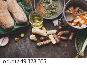 Jerusalem artichoke cooking preparation on rustic kitchen table with pot, diced vegetables, oil and ingredients, top view. Стоковое фото, агентство Ingram Publishing / Фотобанк Лори