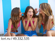 Three teen best friends girls funny whispering gesture in a beach stripes background. Стоковое фото, агентство Ingram Publishing / Фотобанк Лори