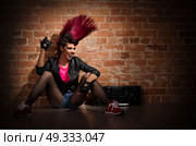 Young punk girl on brick wall background. Стоковое фото, агентство Ingram Publishing / Фотобанк Лори