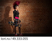 Young punk girl on brick wall background. Стоковое фото, агентство Ingram Publishing / Фотобанк Лори