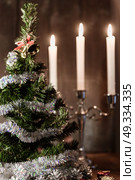 Christmas decorative tree is adorned with rain stands on the table with lit candles. Стоковое фото, агентство Ingram Publishing / Фотобанк Лори