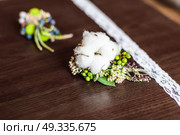 boutonniere made of cotton lying on a brown table with lace. Стоковое фото, агентство Ingram Publishing / Фотобанк Лори