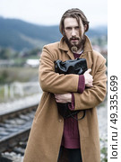 a man in a brown coat stands clutching a black briefcase on a background of mountains. Стоковое фото, агентство Ingram Publishing / Фотобанк Лори